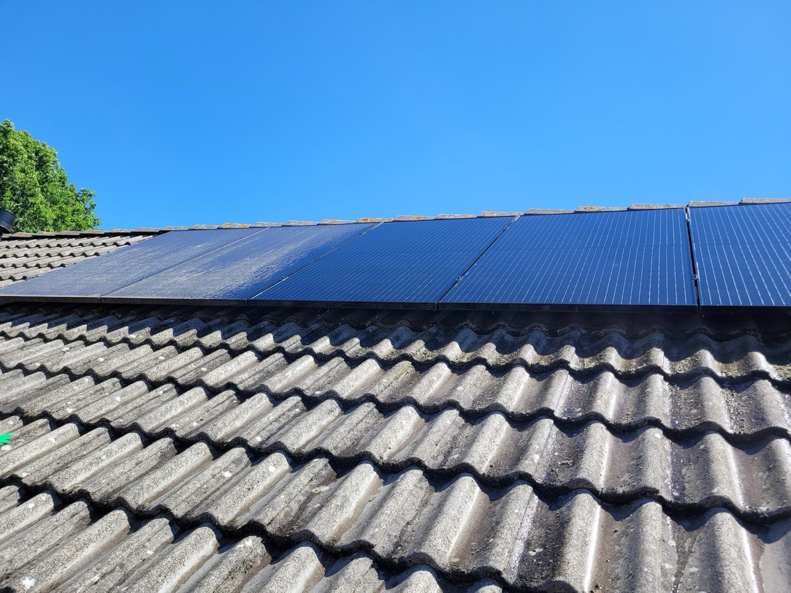 Schone zwarte zonnepanelen op een pannendak onder een blauwe lucht