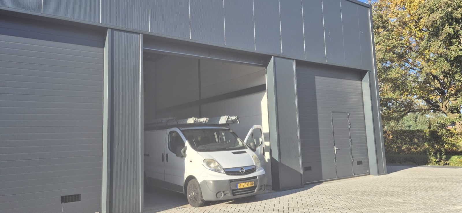 De bus geparkeerd in een grijze bedrijfshal met de roldeur open