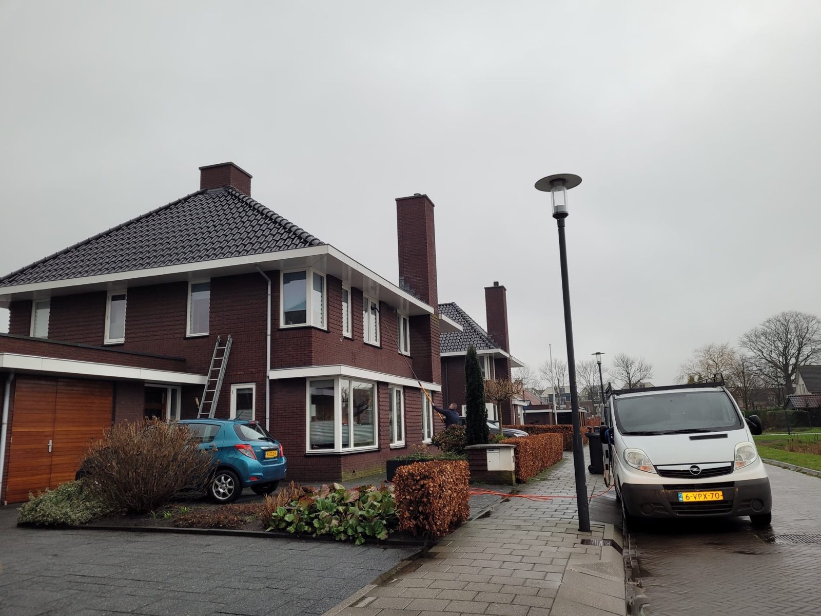 De bus van J. Seip voor een vrijstaande bakstenen woning, met ladder tegen de gevel
